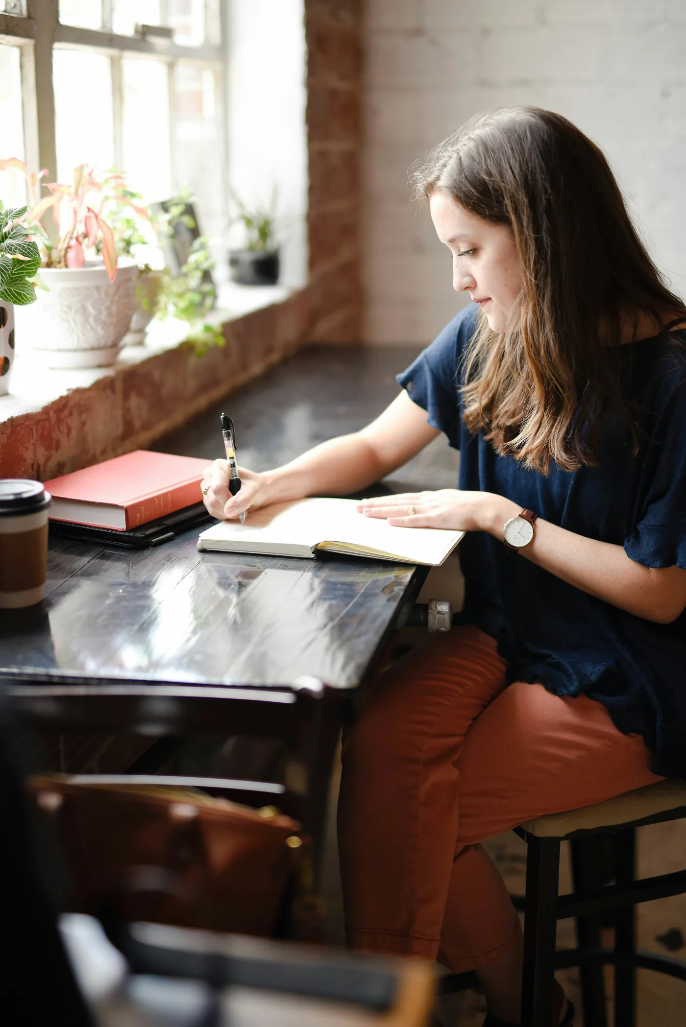 A student writing in a notebook by a window